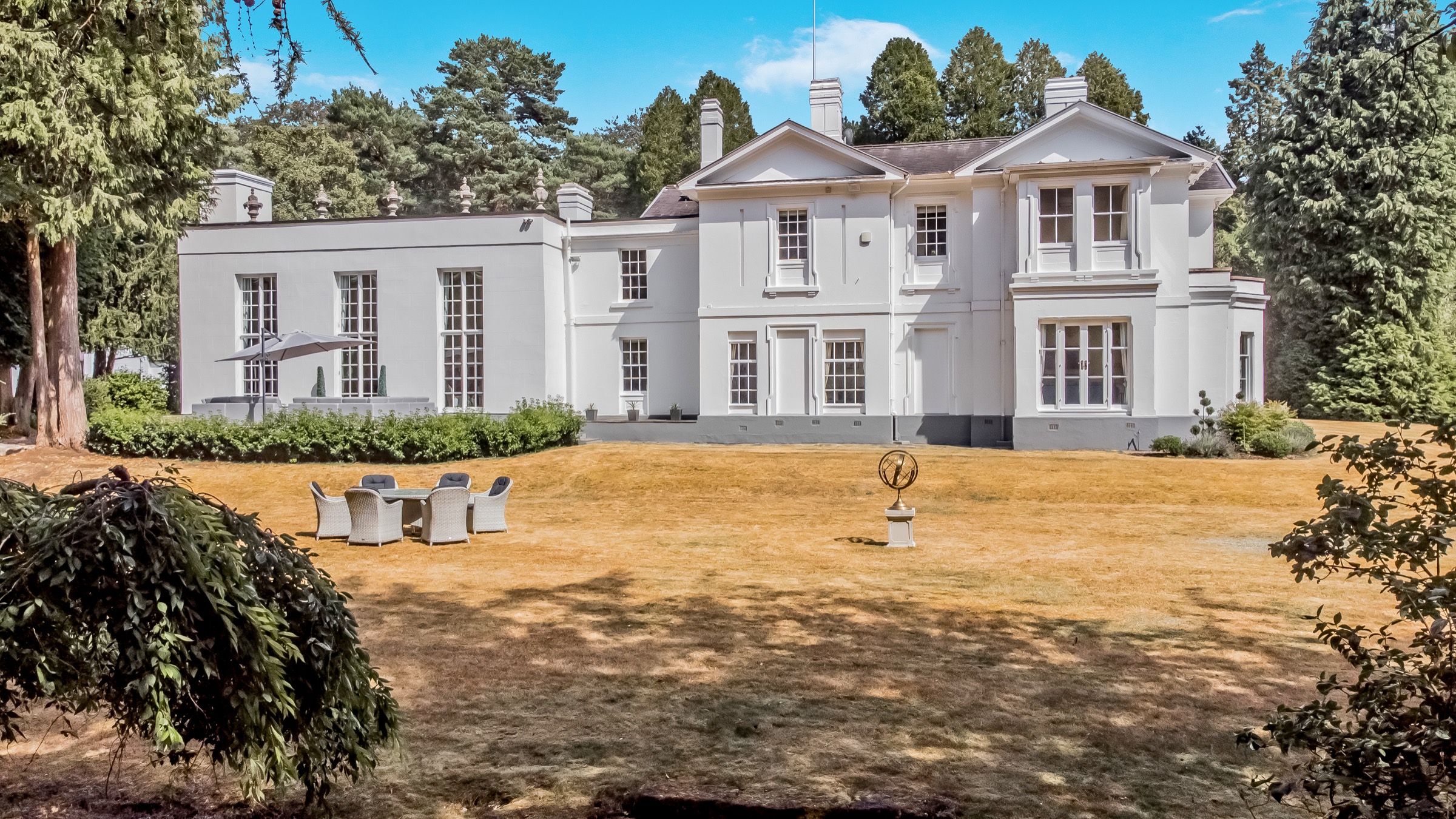 Aerial view of a white period country house and its grounds