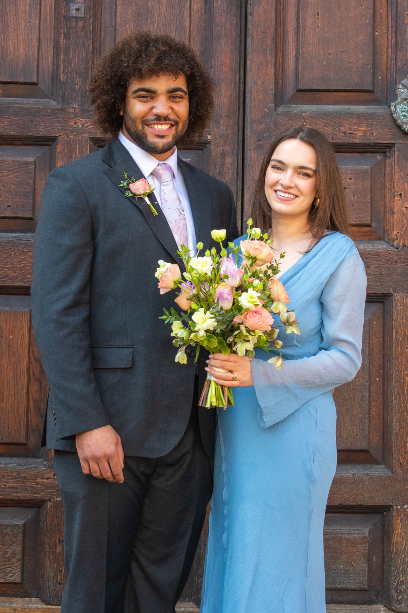 A couple outside the church doors with their bouquet