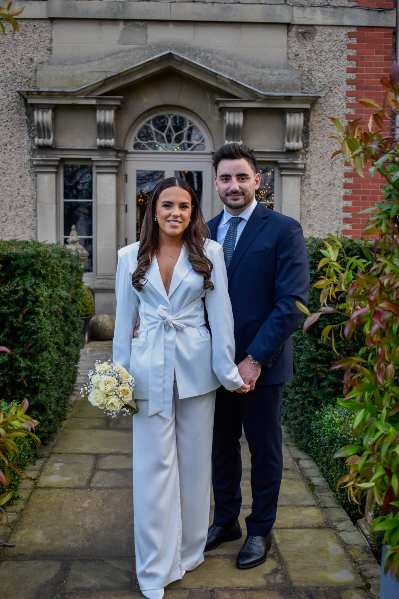 A couple holding hands outside a country house