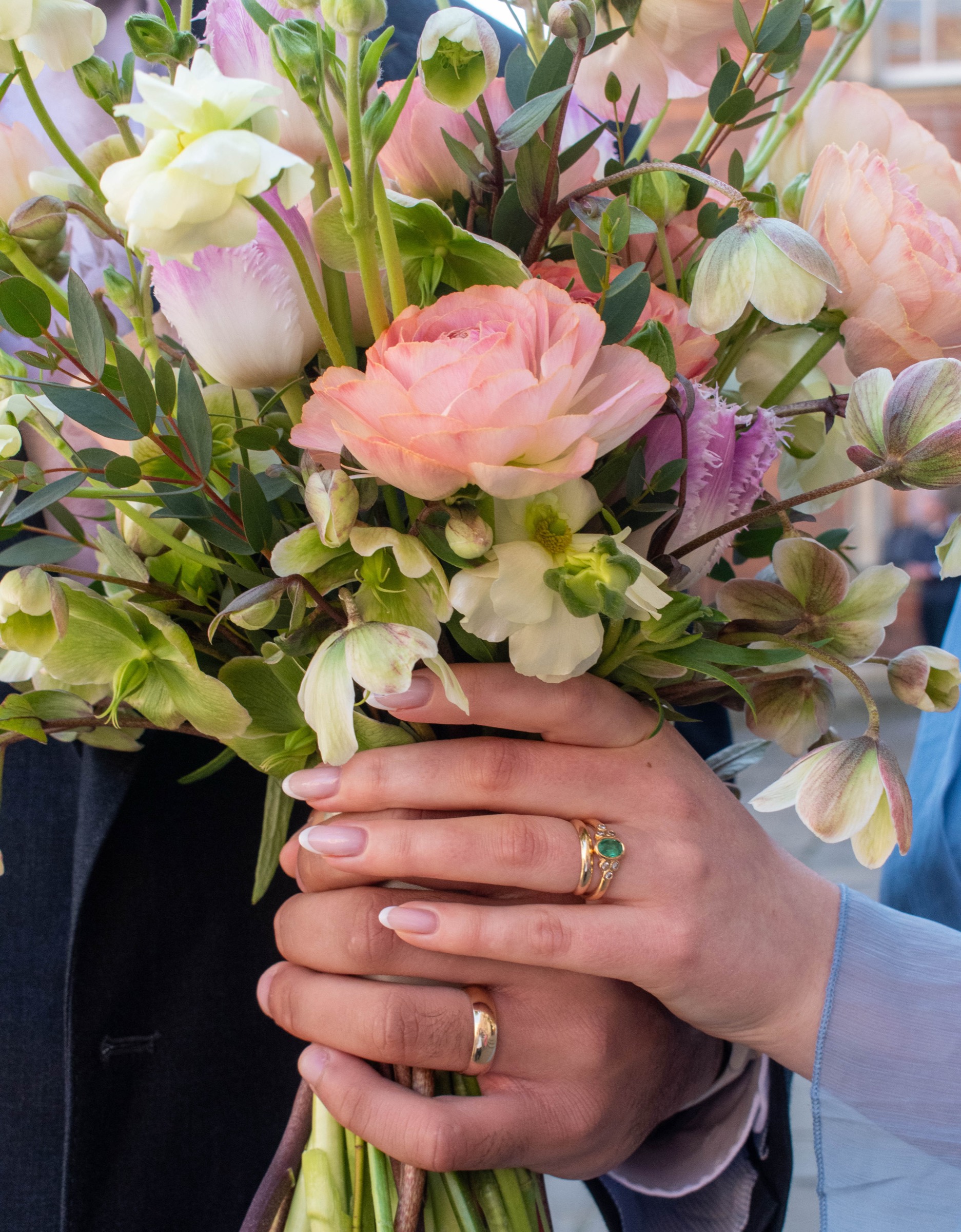 A bride holding her bouquet with the wedding rings visible